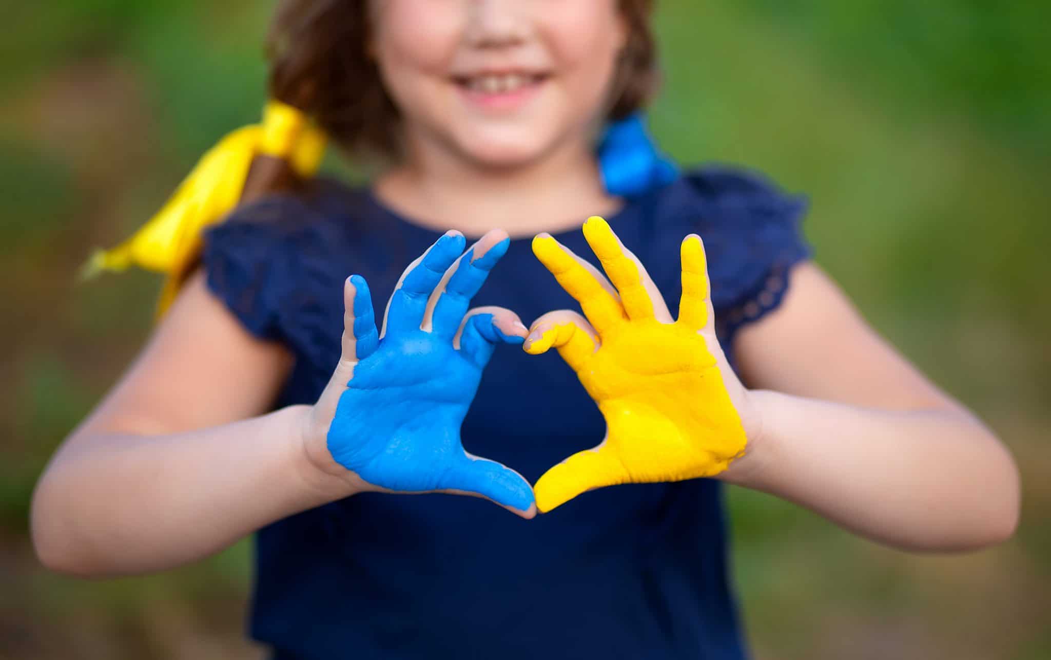 Love Ukraine concept. Little girl show hands in heart form painted in Ukraine flag color - yellow and blue. Independence day of Ukraine, Flag, Constitution day Education, school, art painitng concept