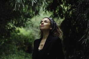 L'artiste Annie Lalalove en pleine nature regarde avec un sourire vers le ciel