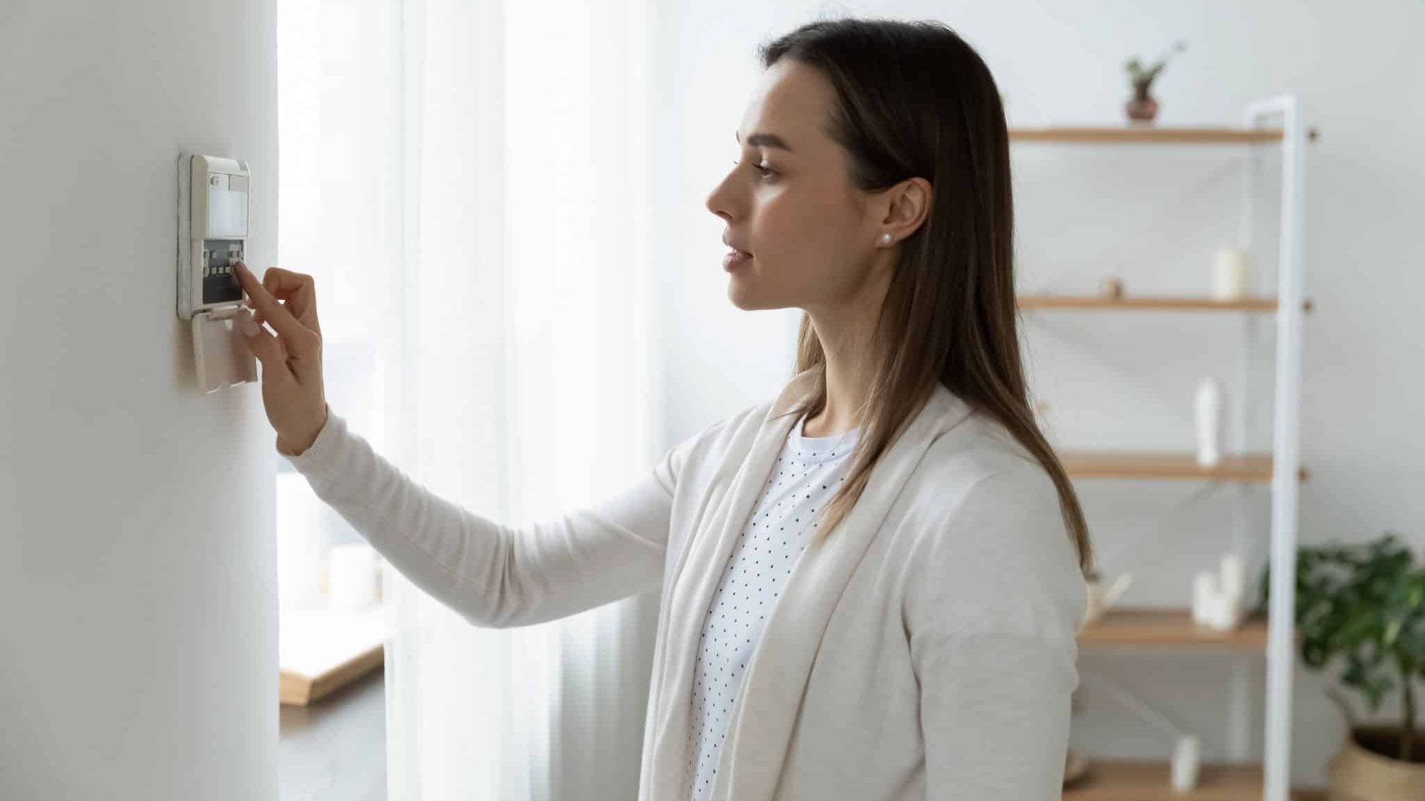 Femme réglant un thermostat pour faire des économies d'énergie