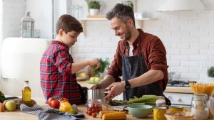 Un homme cuisine avec son fils.