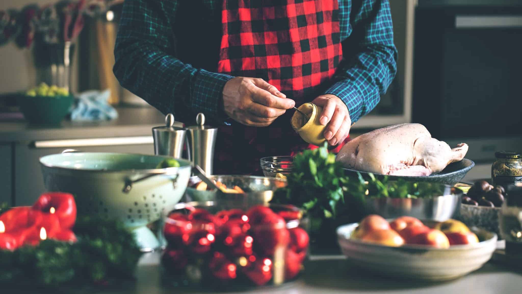 Un homme dans une cuisine avec un pot de moutarde.