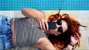 Une femme écoute de la musique au bord d'une piscine.