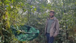 Thomas Caignard, post-doctorant à l’UMR Biogéco à l’université de Bordeaux et de l’INRAe pose à côté d'un arbre de la forêt urbaine de Floirac. Sur cet arbre il y a un filet accroché pour récupérer les glands