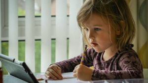 Une petite fille fait ses devoirs avec une tablette