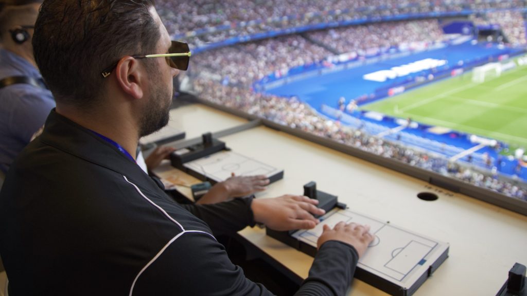 Homme aveugle qui suit un match de football avec la tablette tactile, au Stade de France
